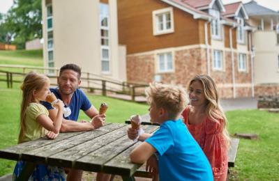 A fmaily eating ice cream on a bench outside Wookey Hole hotel - Credit Wookey Hole