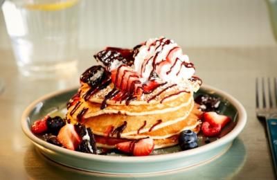 A plate of stacked pancakes with berries and cream on top - Credit Mollie's Motel and Diner