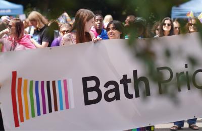 People holding a large white banner that says Bath Pride