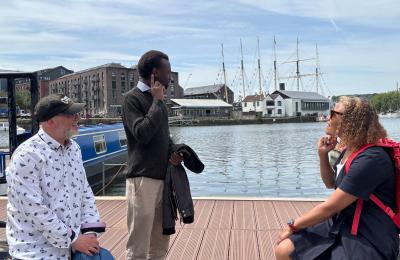 3 people sat on decking next to Bristol Harbour
