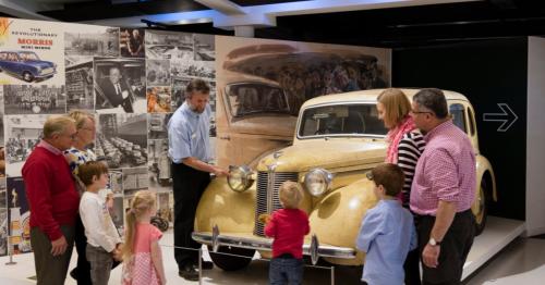 Children and families standing around a classic motor car at the British Motor Museum