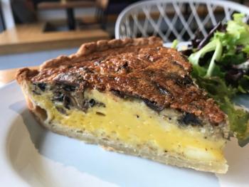 Slice of quiche on plate with salad at Little Eater