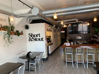 Modern industrial-chic interiors of Short & Stout restaurant featuring plants, tables & chairs and a bar