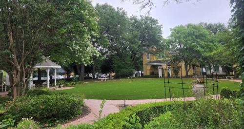 Big yellow carriage house in the distance with gardens and gazebo