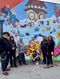 Artists posing in front of colorful mural in downtown Gilroy