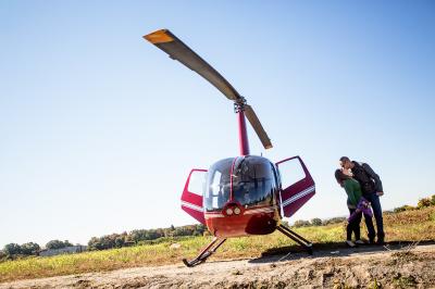 A couple kissing standing next to a helicopter