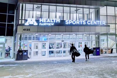 Father and son walking into M Health Fairview Sports Center with hockey gear.