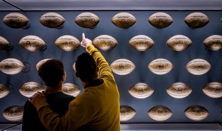 Father and son looking at and pointing to footballs in the Green Bay Packers Hall of Fame
