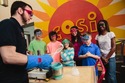 Scientist with gloves and tongs performing chemistry experiments for children at COSI