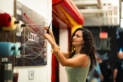 Woman interacts with a textile-inspired art installation at The Loom, a Columbus Fashion Alliance exhibition in Columbus, Ohio.