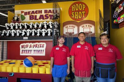 Three staff members posing in front of Hoop Shot at Funland in Rehoboth Beach, Delaware.
