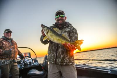 A man smiling and holding a walleye as part of a Cast and Blast on Devils Lake, ND.