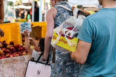 Man carrying box of strawberries near fruit stand