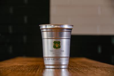 Aluminum glass with Tioga Sequoia logo sits on table.