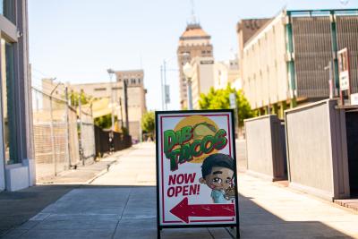 Sidewalk sign reading "Dab Tacos" with Fresno skyline in the background.
