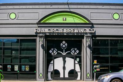 Exterior of Full Circle Brewing with large sign, skull mural and lime green finish.