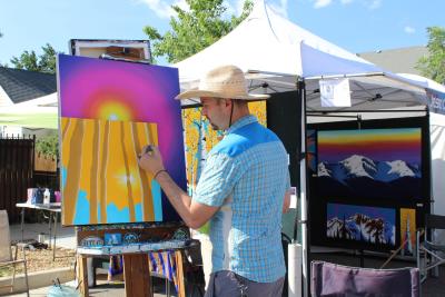 Local artist Jesse Crock painting outside at his booth during a summer arts festival