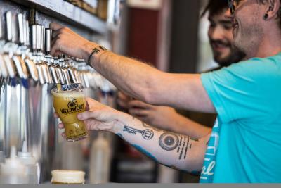 Bartender pouring a beer from the tap at WeldWerks Brewing Co.