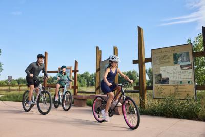 Family Biking outdoors on the Poudre River Trail with sign behind them