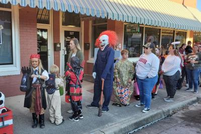 People dressed in costumes along Reid Ave as they go trick or treating