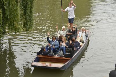 A group of people waving at the camera on a punt tour in Cambridge