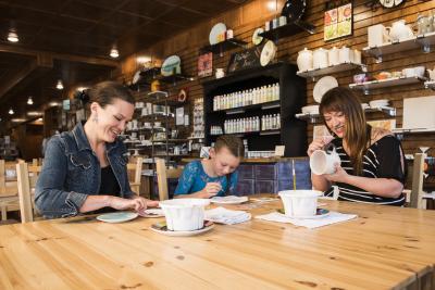 Adults and a kid painting pottery at Earth Goods