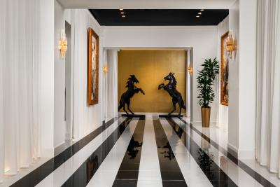A hallway with black and white striped floors, white curtain and black horse statues