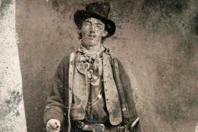 Bill the Kid poses for a ferro-type photo outside a Fort Sumner saloon in 1879 with a Winchester carbine and Colt revolver.