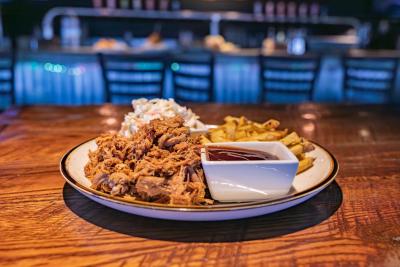 Plate with pulled pork, fries, and coleslaw with bbq on the side