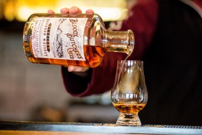 A bartender pouring a snifter of bourbon at Jeptha Creed Distillery in Shelbyville, KY