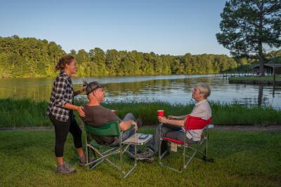 Family laughing together and sitting in camping chairs at Lake Claiborne