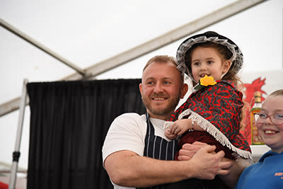 Jonathan Woolway holding a small girl in Welsh dress.