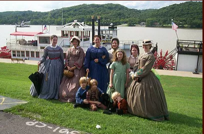 Women in nineteeth century dresses in front of a paddlewheeler on the Ohio river