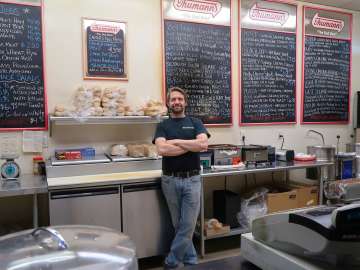 Owner of Sidewalk Deli behind the counter
