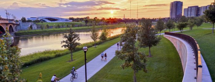 People walk and bike along Scioto Mile in Columbus at sunset.
