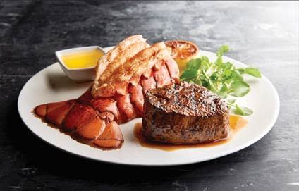 Lobster tail and steak on white plate with garnish and butter