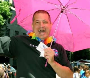 A joyful man holding a pink umbrella at a Pride Festival