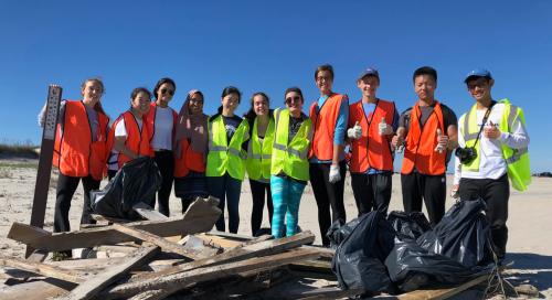 A beach clean-up crew in safety vests poses with the debris they collected on the OBX.