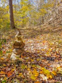 Autumn leaves line the trail and a cairn at Charlestown State Park Trail.