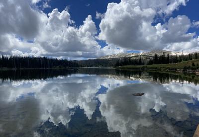 Clouds reflecting on lake with mountains and trees