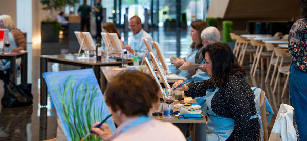 A group of people painting on canvas in the Mulva Cultural Center facilities.