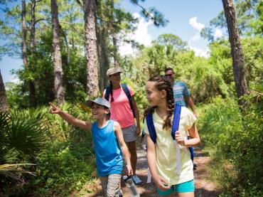 Parents and two kids hiking through green trees in Punta Gorda/Englewood Beach