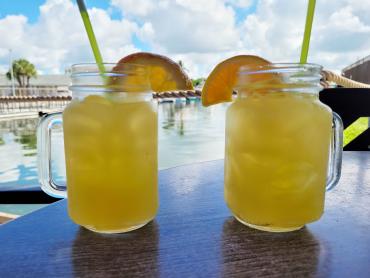 Two orange cocktails on a table overlooking the water at SandBar Tiki & Grille in Englewood, FL