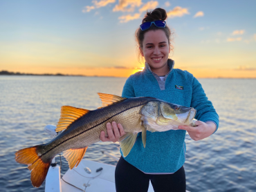 Woman in blue sweatshirt holding a freshly-caught snook