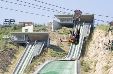 Man and woman riding down zip line at Utah Olympic Park