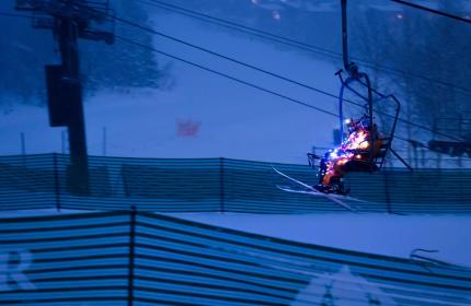 Skiers dressed in lights ride a chairlift at dusk near Park City, UT