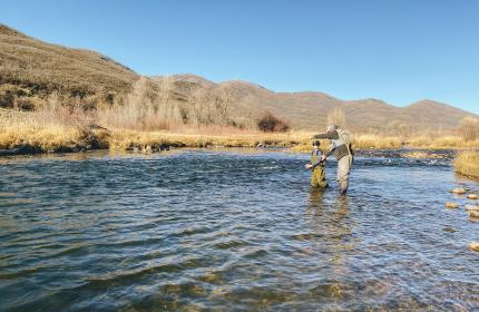 Instructor and student in the water learning fly fishing