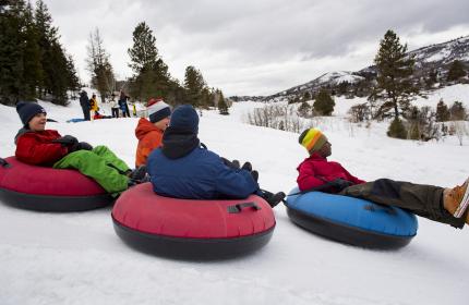 four teenagers tubing down a hill