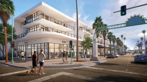 A sunny streetscape with modern two-story white buildings on the left, palm trees lining the road, pedestrians, some with a dog, crossing the street, cars on the road, and a traffic light showing green.