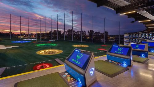 Golf bays at Topgolf Woodbury with sun setting in the background
